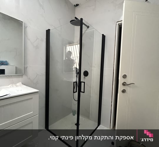 מקלחון פינתי שקוף עם פרופילים שחורים שהותקן בחדר רחצה
